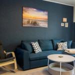 Ein Wohnzimmer mit blauem Sofa, einem Schaukelstuhl und einer Wanddekoration.