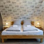 Schlafzimmer mit Doppelbett, Textildruckwand und Holzmöbeln.