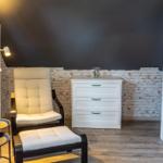 Schlafzimmer mit Stuhl, Nachttisch, Schrank und weißem Schrank.