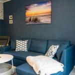 Ein Wohnzimmer mit blauem Sofa, Wandbild und dekorativen Kissen.