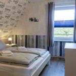 Schlafzimmer mit Doppelbett, Fenster und Schrank. Wand mit Reisemotiv und Holzoptik.