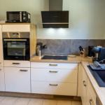 Küche mit Kühlschrank, Herd, Spüle und Fenster.