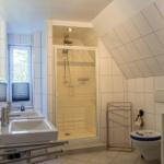 Badezimmer mit Dusche, Toilette und Waschbecken unter schrägem Dach