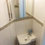 Badezimmer mit Waschbecken, Spiegel und Handtuchhalter.