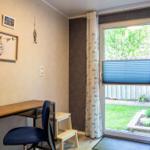 Schreibtisch mit Stuhl und Fensterblick auf Garten.