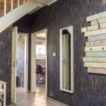 Eingangsbereich mit dunkler Tapete, Holzbank, Wandgarderobe und Treppenhaus.