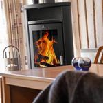 Kaminofen mit brennendem Feuer, Holztisch und Stühle im Raum mit Holzwand.