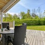 Terrasse mit Tisch und Stühlen, Blick auf grünen Garten und Bäume.