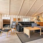 Wohnraum mit Kamin, Sofa, Stühlen und Holzwandverkleidung.