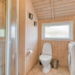 Bad mit Dusche, Toilette und Waschmaschine. Holzwandungen und Fenster mit Jalousie.