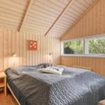 Schlafzimmer mit Holzwand, Bett und Fenster zum Blick auf Bäume.