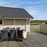 Terrasse mit Tisch und Stühlen vor einem Haus mit Holzveranda.