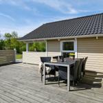 Terrasse mit Tisch und Stühlen vor einem Haus mit Holzfassade und Dach.