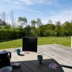 Terrasse mit Tisch, Stühlen und Blick auf den Garten mit Schaukel.