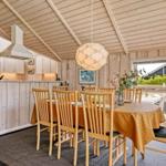 Essbereich mit Holztisch, Stühlen und Küchenzeile unter Holzdecke.