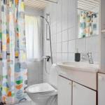 Badezimmer mit Dusche, Waschbecken und Toilette. Farbiger Duschvorhang und Spiegel.