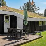 Haus mit Grasdach, Terrasse mit Tisch, Stühlen und Sonnenschirm.