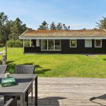 Holzterrasse mit Tisch, Stühlen und Hängematte vor einem Haus mit Grasfläche und Bäumen.