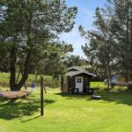 Haus mit grünem Rasen, Hängematten und Bäumen im Hintergrund.