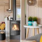 Kamin mit brennendem Feuer, Sofa mit Kissen, Holzwände und Pflanzen auf Tisch