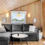 Wohnzimmer mit grauem Sofa, runden Tisch und Holzwandverkleidung.