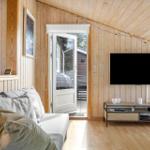 Wohnzimmer mit Sofa, Fernseher und Tür zum Außenbereich.