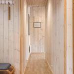Flur mit Holzwandverkleidung, Sitzbank und Blick in Schlafzimmer mit Bett.
