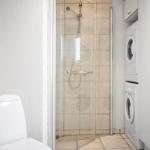 Bad mit Dusche, Toilette und Waschmaschine-Trockner-Kombination.