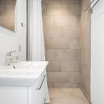 Badezimmer mit Waschbecken, Spiegel und Dusche mit Duschvorhang.