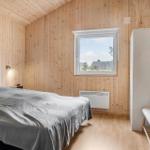 Schlafzimmer mit Holzwand, Bett, Fenster und Kleiderschrank.
