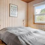 Schlafzimmer mit Bett, Fenster und Holzwandverkleidung.