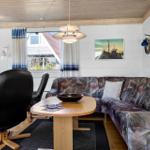 Wohnzimmer mit Sofa, Esstisch und Kaminofen. Holzdecke und weiße Wände.