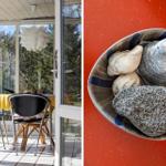 Terrasse mit Tisch und Stühlen, Blick auf Bäume. Schale mit Muscheln und Steinen auf roter Wand.