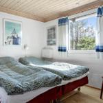 Zwei Betten mit gemusterten Bettdecken, Fenster mit Vorhängen und Stuhl.