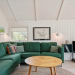 Ein Wohnzimmer mit grünem Sofa, runden Tisch und Wandbildern.