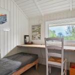 Schlafzimmer mit Bett, Schreibtisch und Fensterblick auf Bäume.