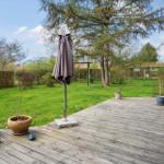 Terrasse mit zwei geschlossenen Sonnenschirmen und Garten im Hintergrund.