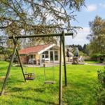 Haus mit Garten, Schaukel und Terrasse unter Bäumen.