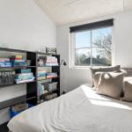 Schlafzimmer mit Bett, Fenster und Bücherregal.