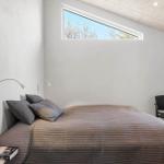 Schlafzimmer mit Bett, Stuhl und schmalen Fenster.