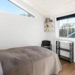 Schlafzimmer mit Bett, Fenster und Schrank. Blick auf Bäume und Himmel.
