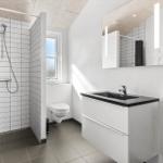 Badezimmer mit Dusche, Toilette und Waschbecken mit Spiegel