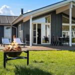 Haus mit Terrasse, Garten und brennendem Feuerkorb.
