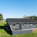 Ein graues Ferienhaus mit Terrasse und Blick aufs Meer.