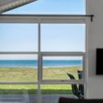 Großes Fenster mit Blick auf Meer und Grasfläche