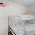 Schlafzimmer mit weißem Doppelstockbett und Kleiderschrank. Wandverkleidung und Holzboden.