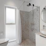 Bad mit Dusche, Waschbecken und Toilette. Terrazzo-Boden und -Wand.