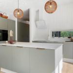 Moderne Küche mit grauen Schränken, Kücheninsel und runden Pendelleuchten.
