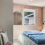 Schlafzimmer mit Holzwand, Bett mit blauer Decke und Fenster.
