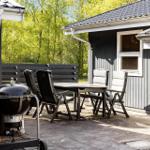 Terrasse mit Tisch, Stühlen und Grill vor einem Haus.